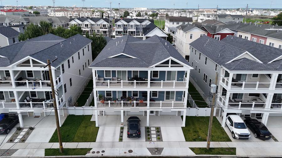 Three new white homes side by side, each with three levels of balconies